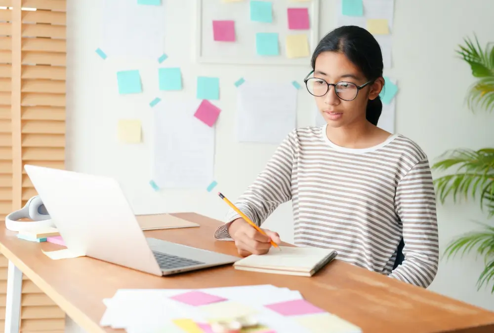 Person studying at desk with laptop.