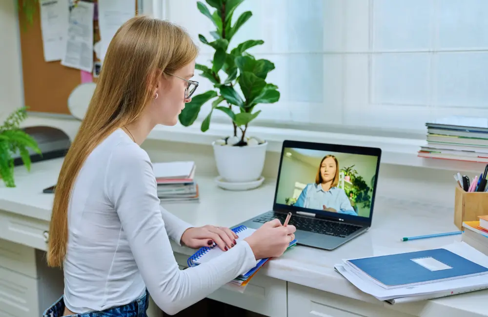 Woman in online meeting, taking notes.