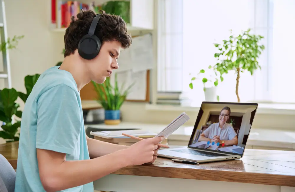 Teen studying online with laptop and headphones.