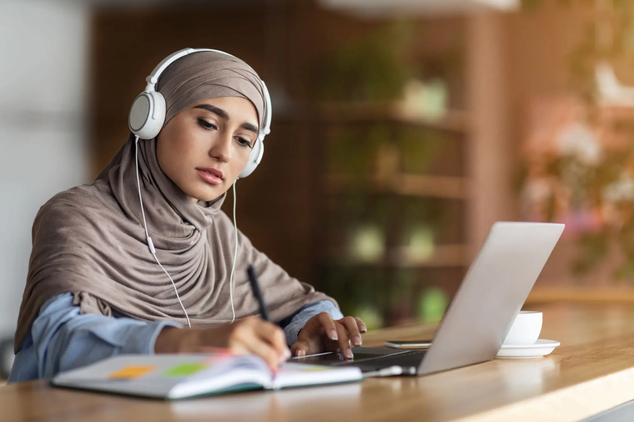 Woman wearing hijab studying with laptop