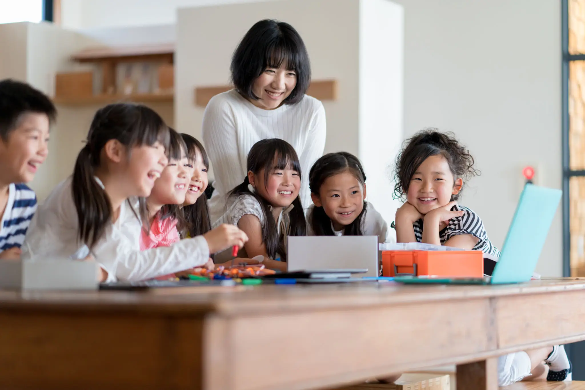 Teacher and children smiling around laptop